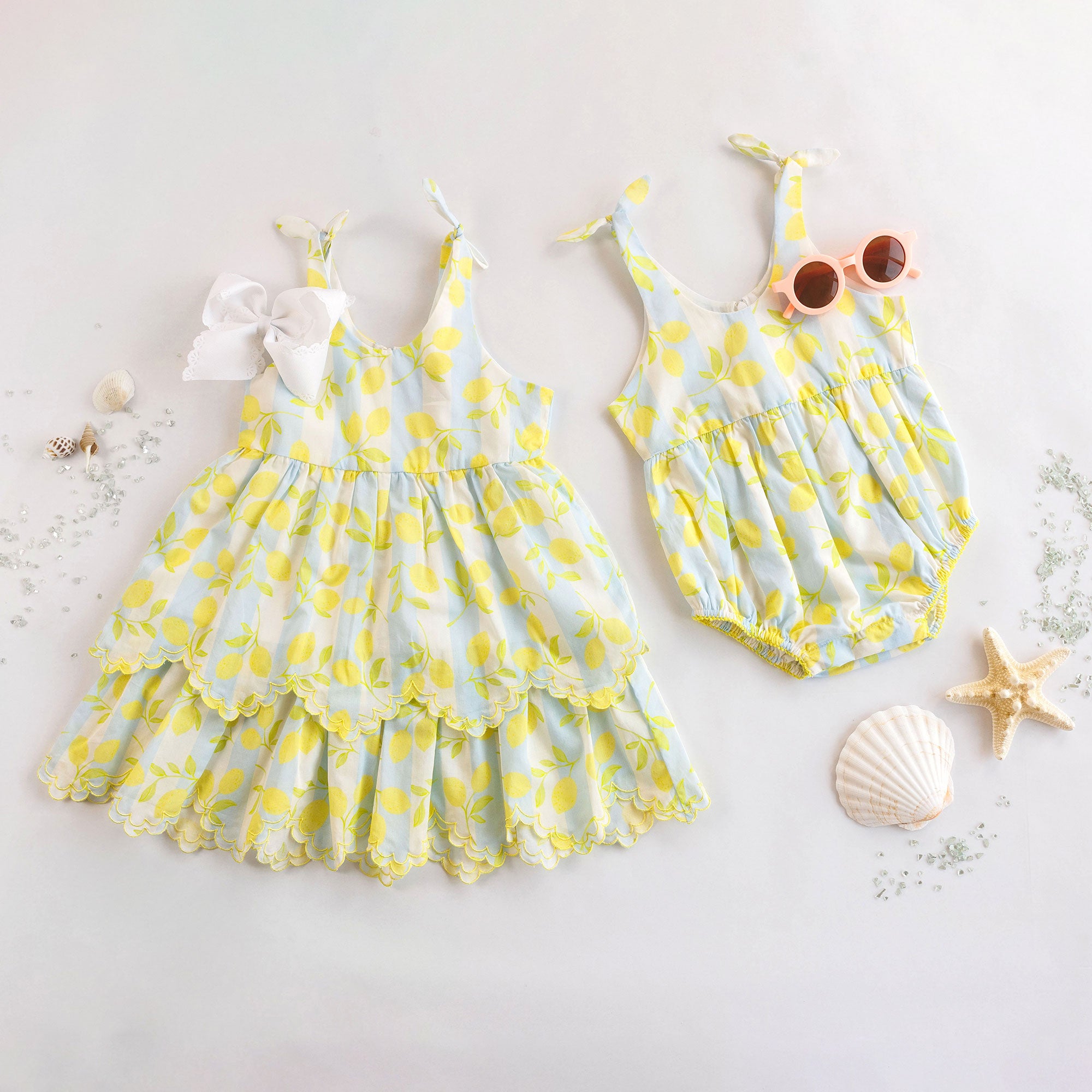 Two children's outfits with yellow lemon patterns on a light background.