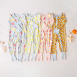 Four colorful baby rompers on a light surface with decorative elements.