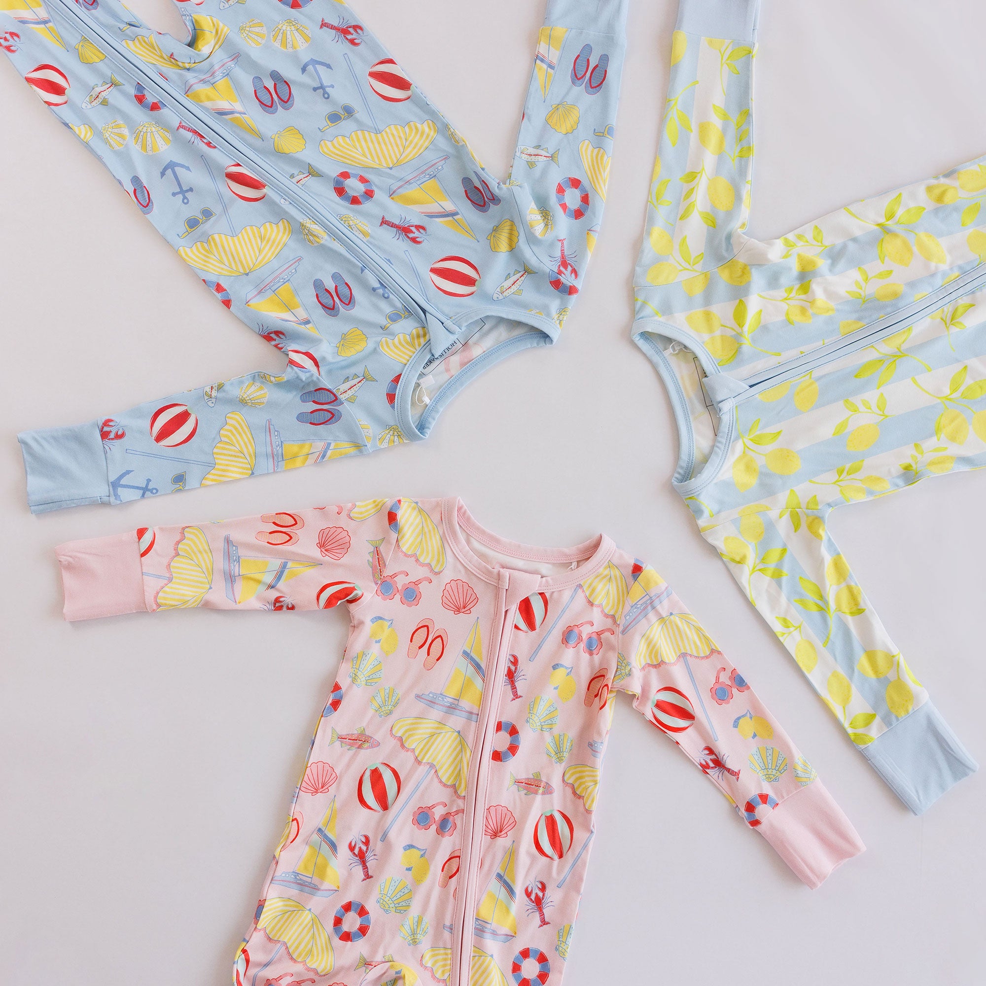 Assortment of several colorful baby zipper rompers on a white background