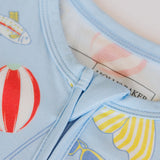Close-up of a light blue fabric with colorful patterns including a red and white striped balloon and yellow and white striped sailboat.