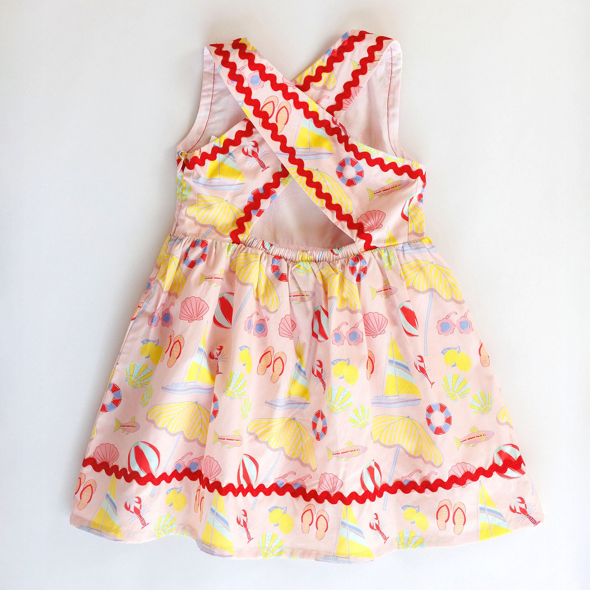 Colorful children's dress with beach-themed pattern on a white background