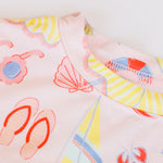 Close-up of a fabric with colorful beach-themed patterns on a light background