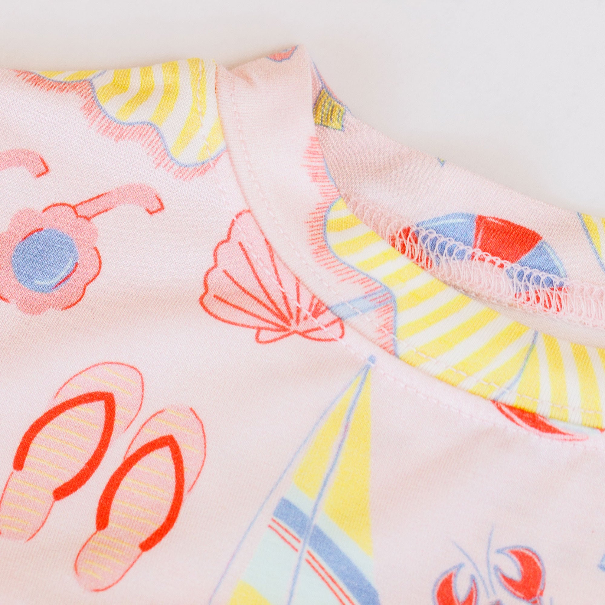 Close-up of a fabric with colorful beach-themed patterns on a light background