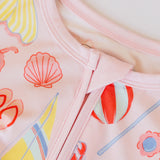 Close-up of a pink garment with colorful shell and flower patterns.
