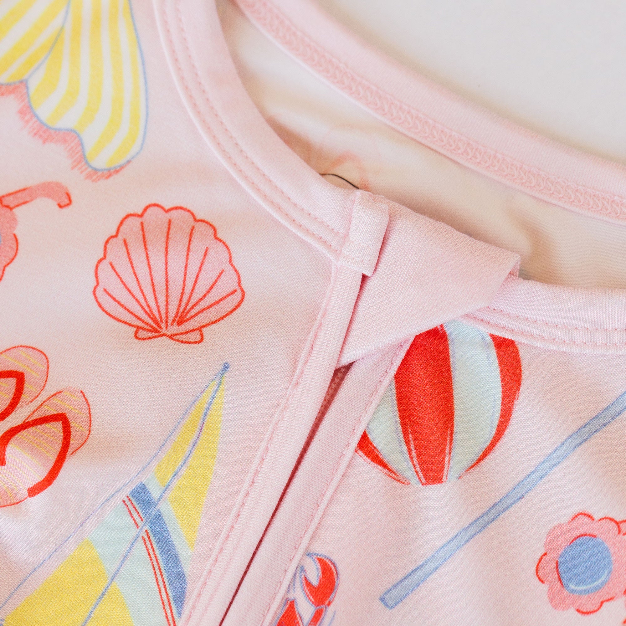 Close-up of a pink garment with colorful shell and flower patterns.