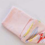 Folded pink fabric with colorful pattern on a light gray background