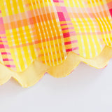 Close-up of a colorful plaid fabric with a scalloped edge on a white background